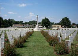 Ranville War cemetery with gravestones in a row leading up to the Cross of Sacrifice