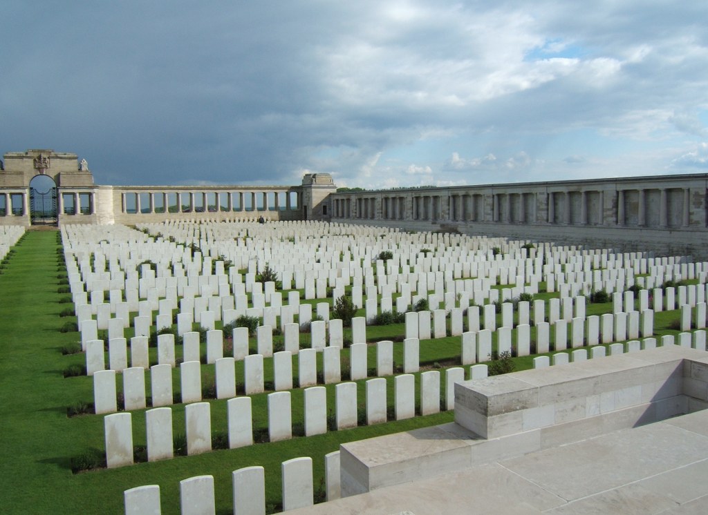 Long rows of white gravestones in the foreground with a colonnaded memorial in the background